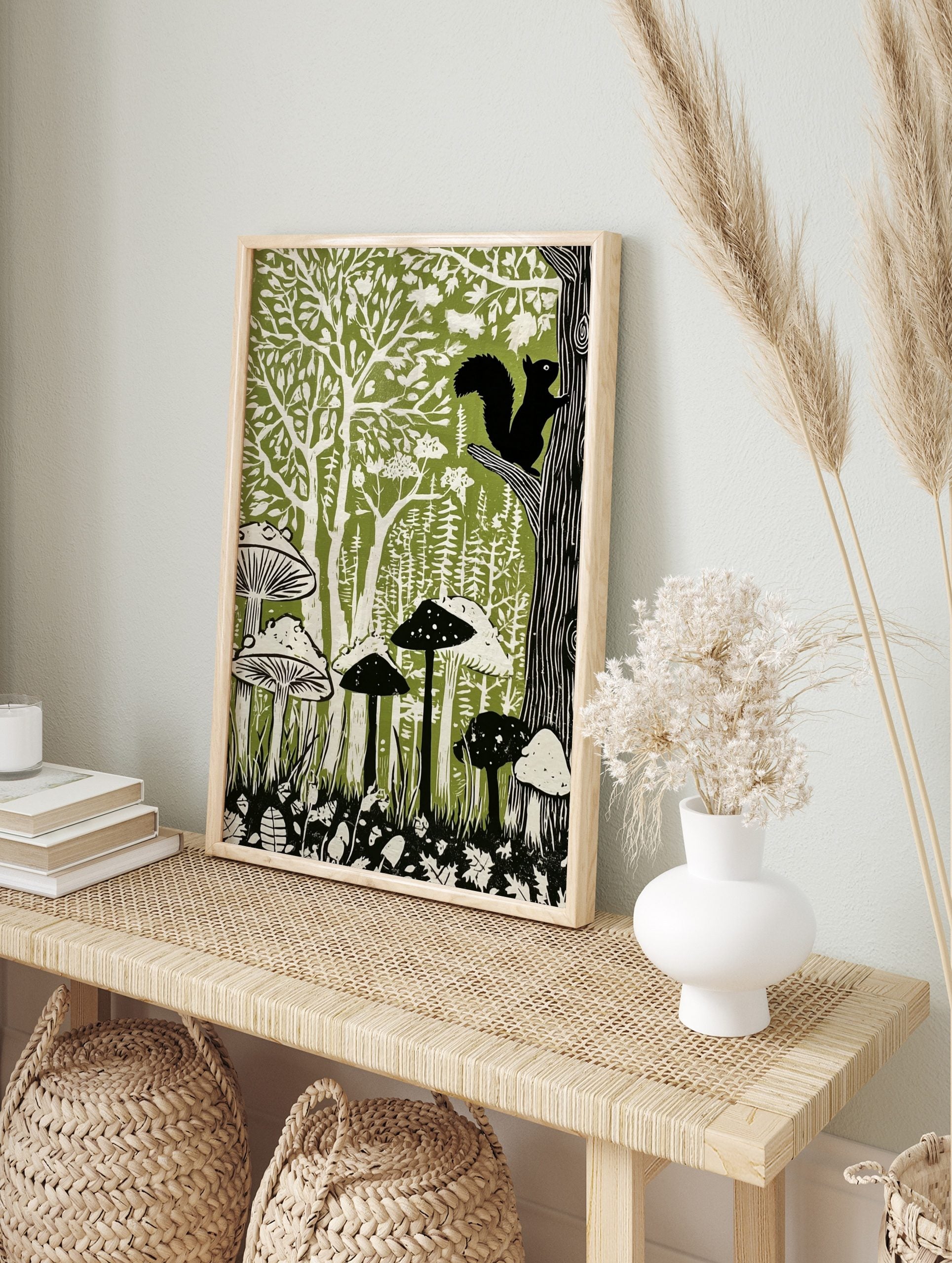Linocut-style forest art print with black squirrel, green trees, and white mushrooms on a, in an alternate framed mockup