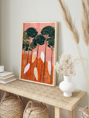 Illustrative art print of six white and beige owls perched on trees with pink sky and orange, in an alternate framed mockup