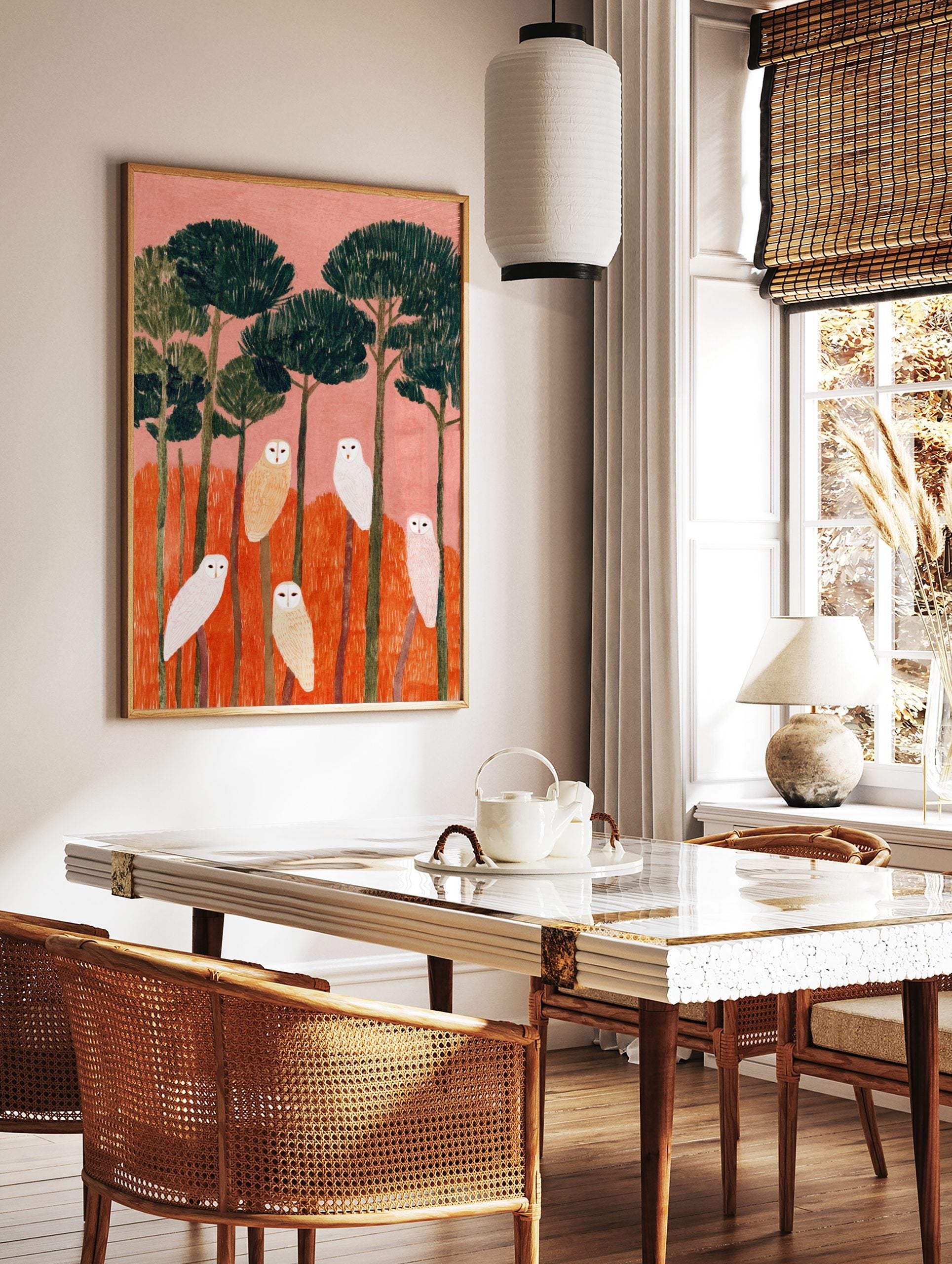 Illustrative art print of six white and beige owls perched on trees with pink sky and orange, in a styled room mockup