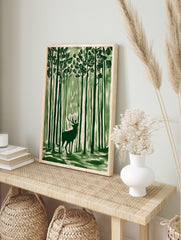 Green illustrative wall art print of a stag with antlers standing in a tall forest, looking, in an alternate framed mockup