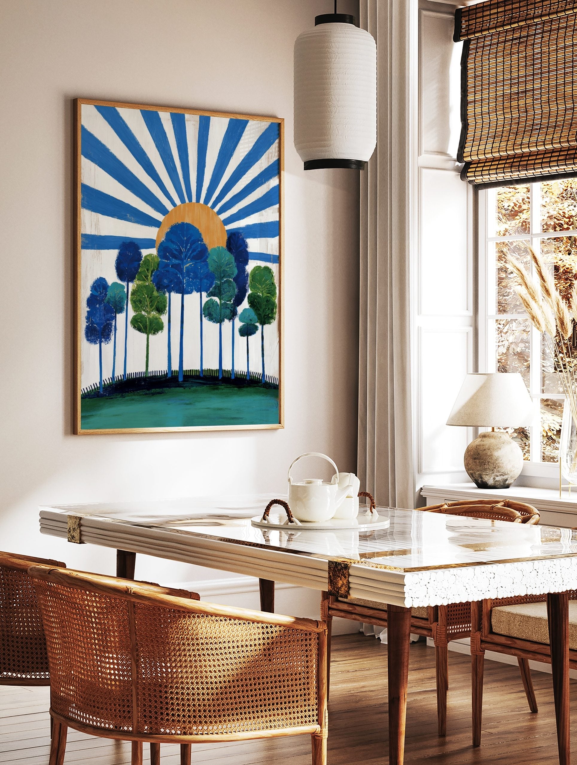 Stylised blue and green trees on a hill with an orange sun and radiating blue rays on a white, in a styled room mockup