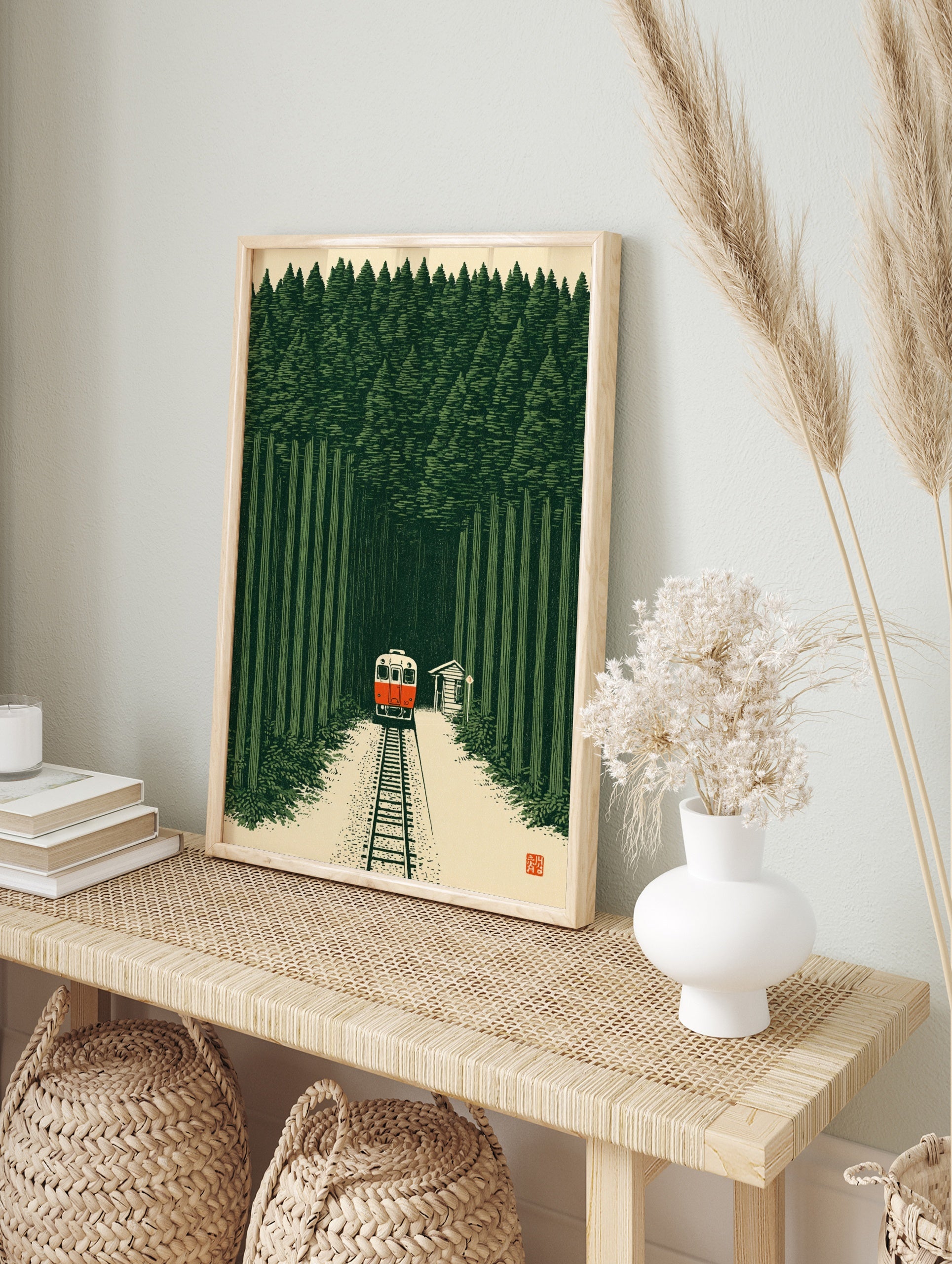 Illustrative art print of a red train travelling through a dense green forest with a small, in an alternate framed mockup
