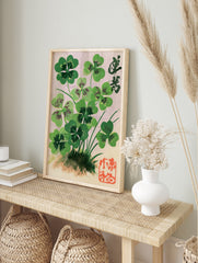 Botanical illustration of four-leaf clovers with Japanese calligraphy and a red seal stamp on, in an alternate framed mockup