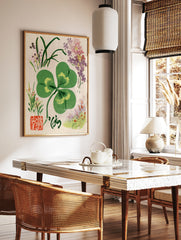 Four-leaf clover botanical illustration with corner flowers, calligraphy, and red seal on paper, in a styled room mockup