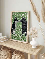 Black fox and bear in profile, surrounded by white wildflowers and green foliage, in a, in an alternate framed mockup