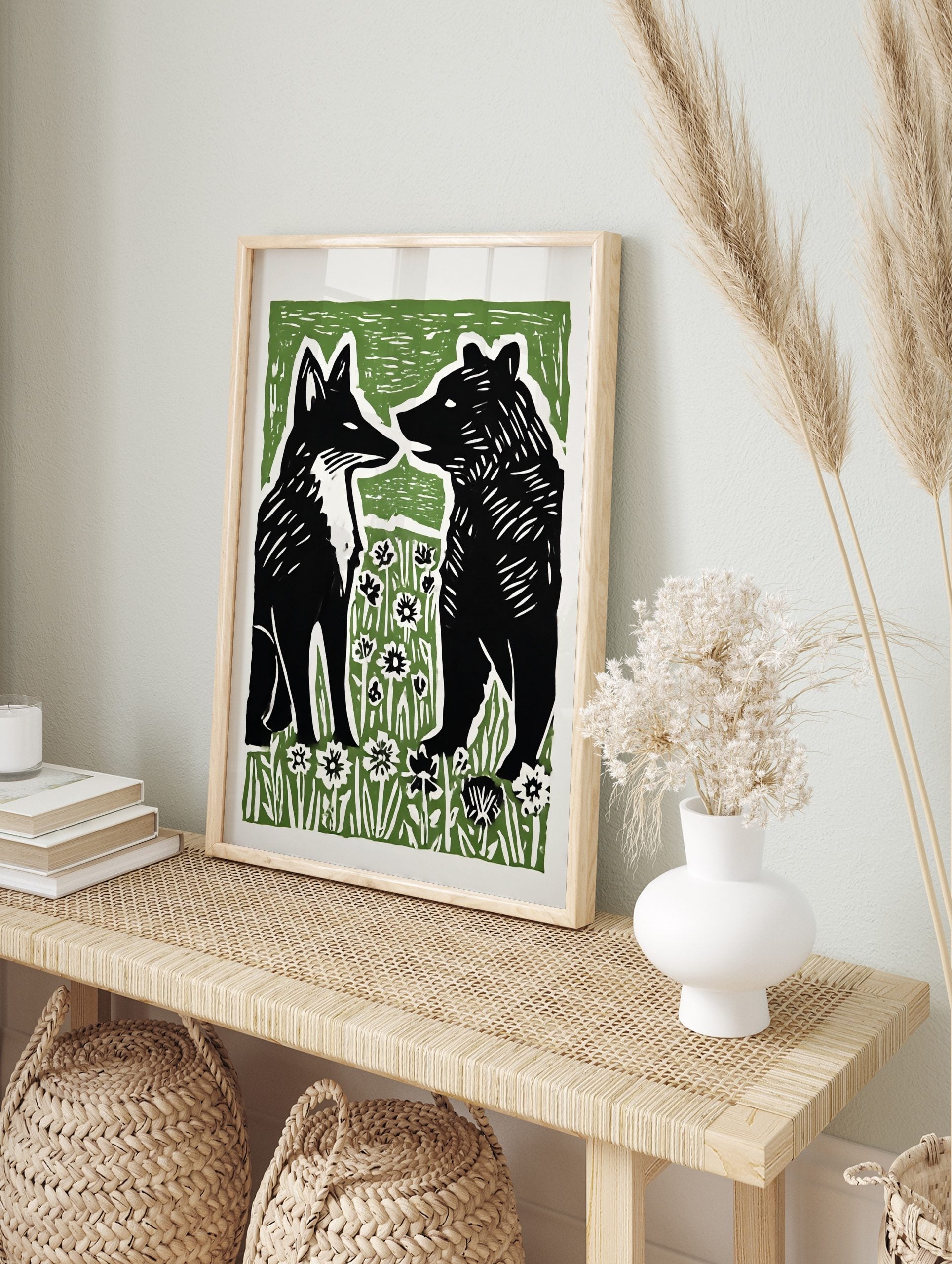 Stylised black fox and bear illustration facing each other in green and white flower field, in an alternate framed mockup