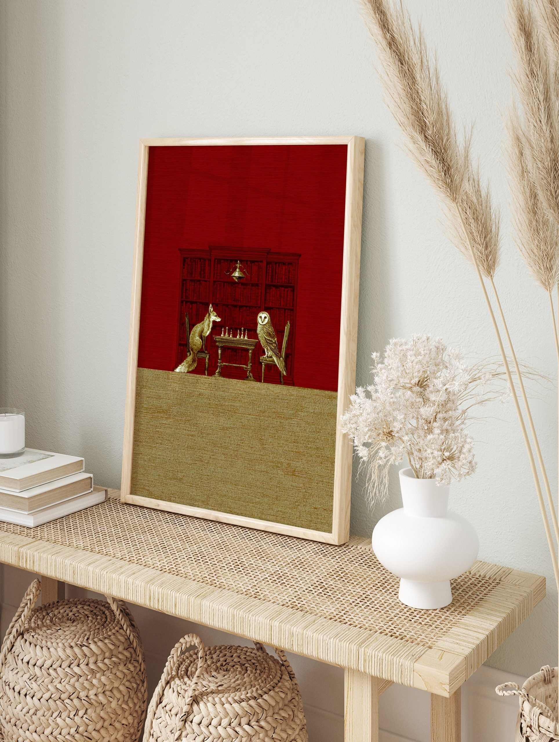 Illustrative print of a fox and an owl playing chess at a table, against a red bookshelf, in an alternate framed mockup
