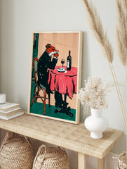 Illustrative print of a fox in a suit drinking red wine at a table with a red tablecloth, in an alternate framed mockup