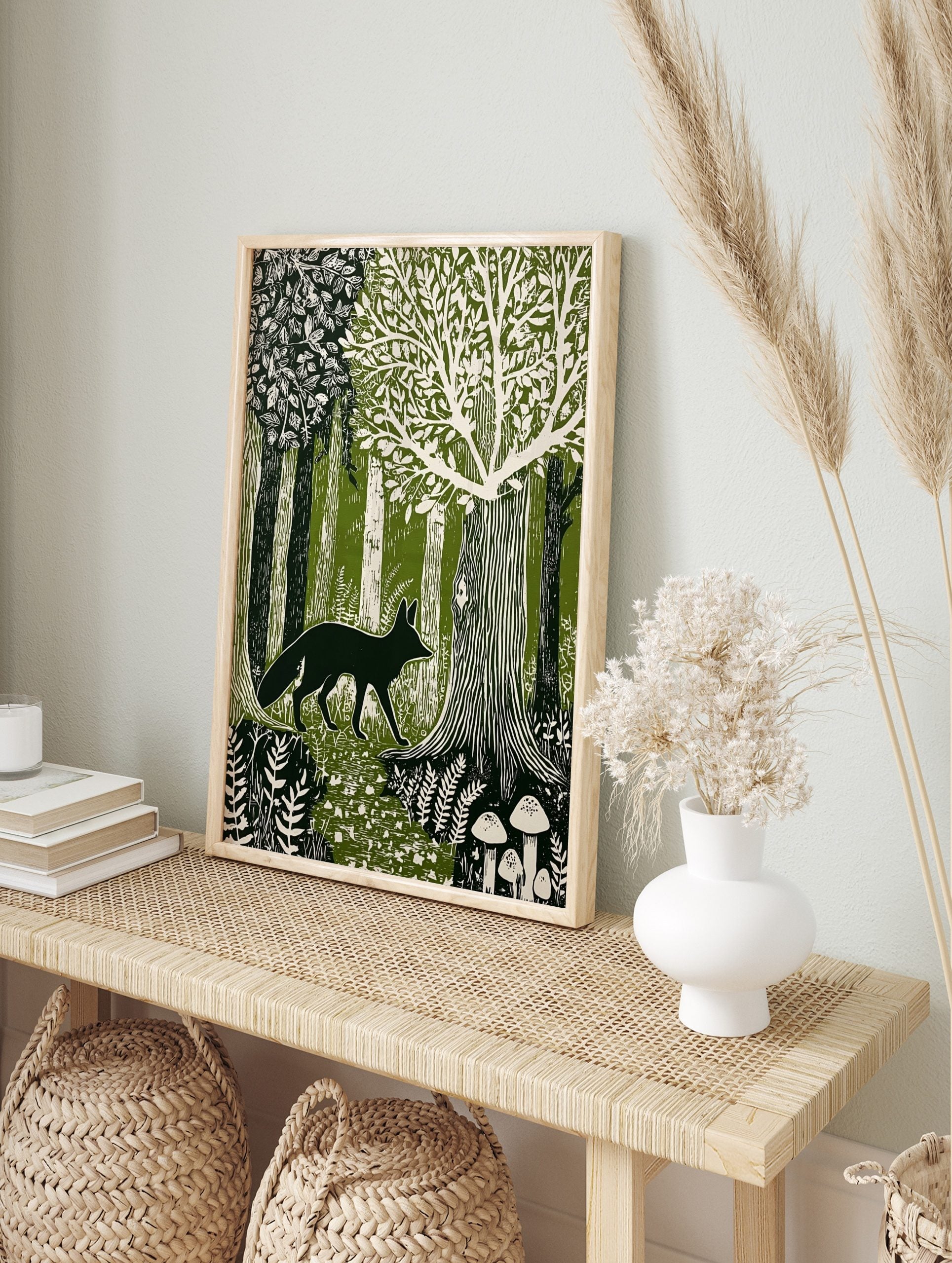 Linocut style print of a dark green fox walking through a cream and green forest with trees, in an alternate framed mockup