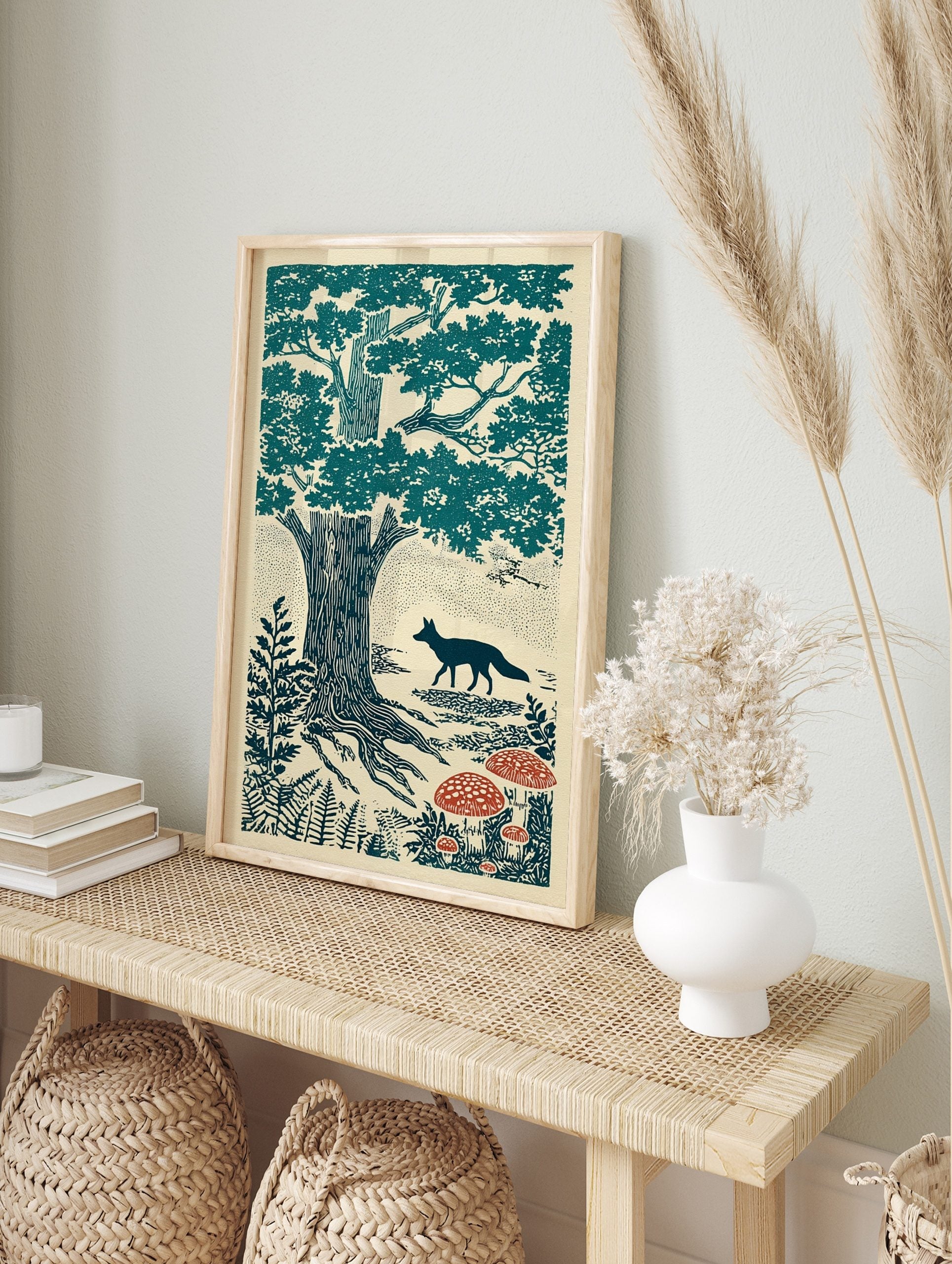 Illustrative teal and red print of a fox walking past oak trees and mushrooms in a forest, in an alternate framed mockup