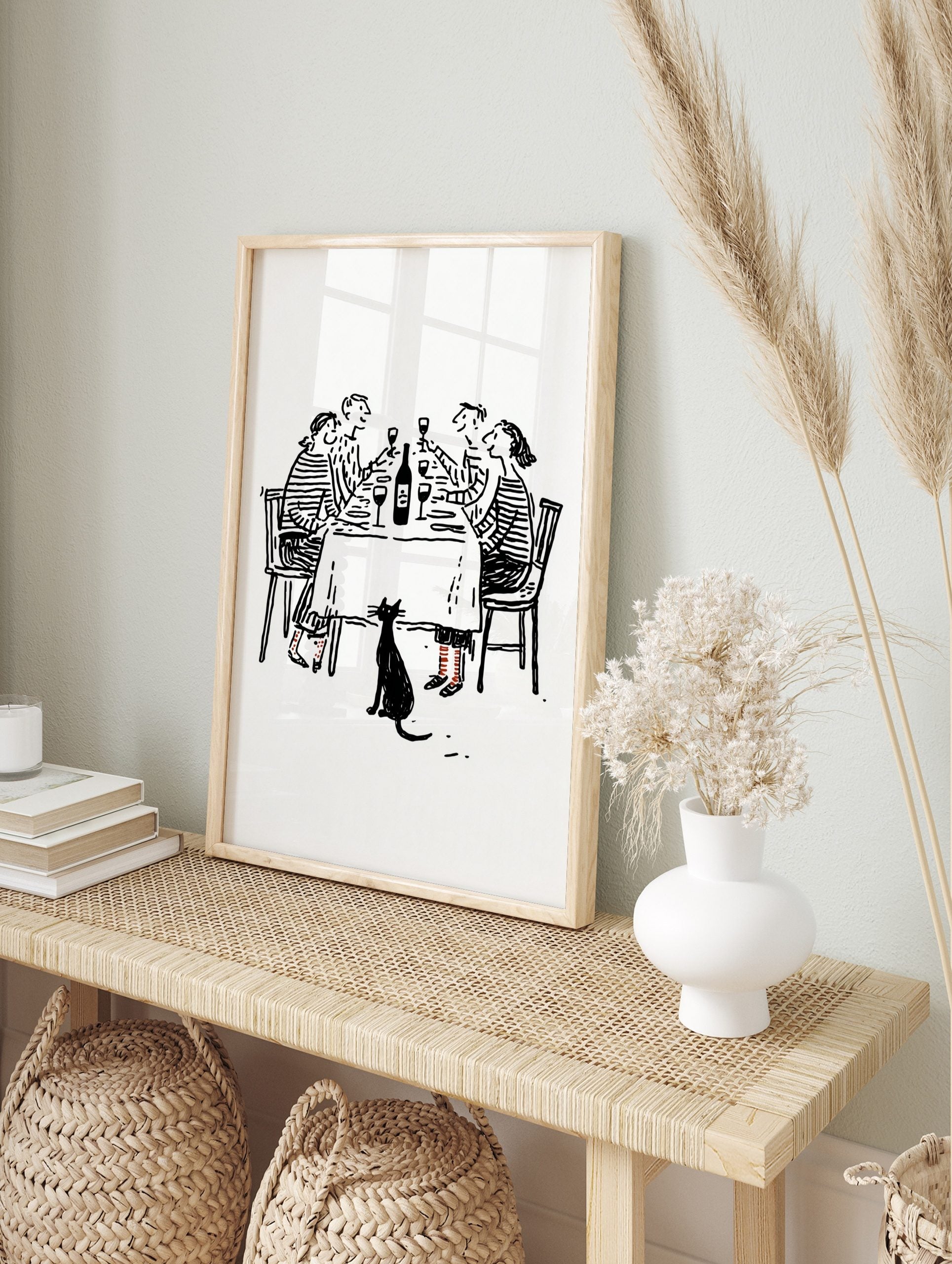 Black and white line drawing of four friends at a dinner party with a black cat below the, in an alternate framed mockup