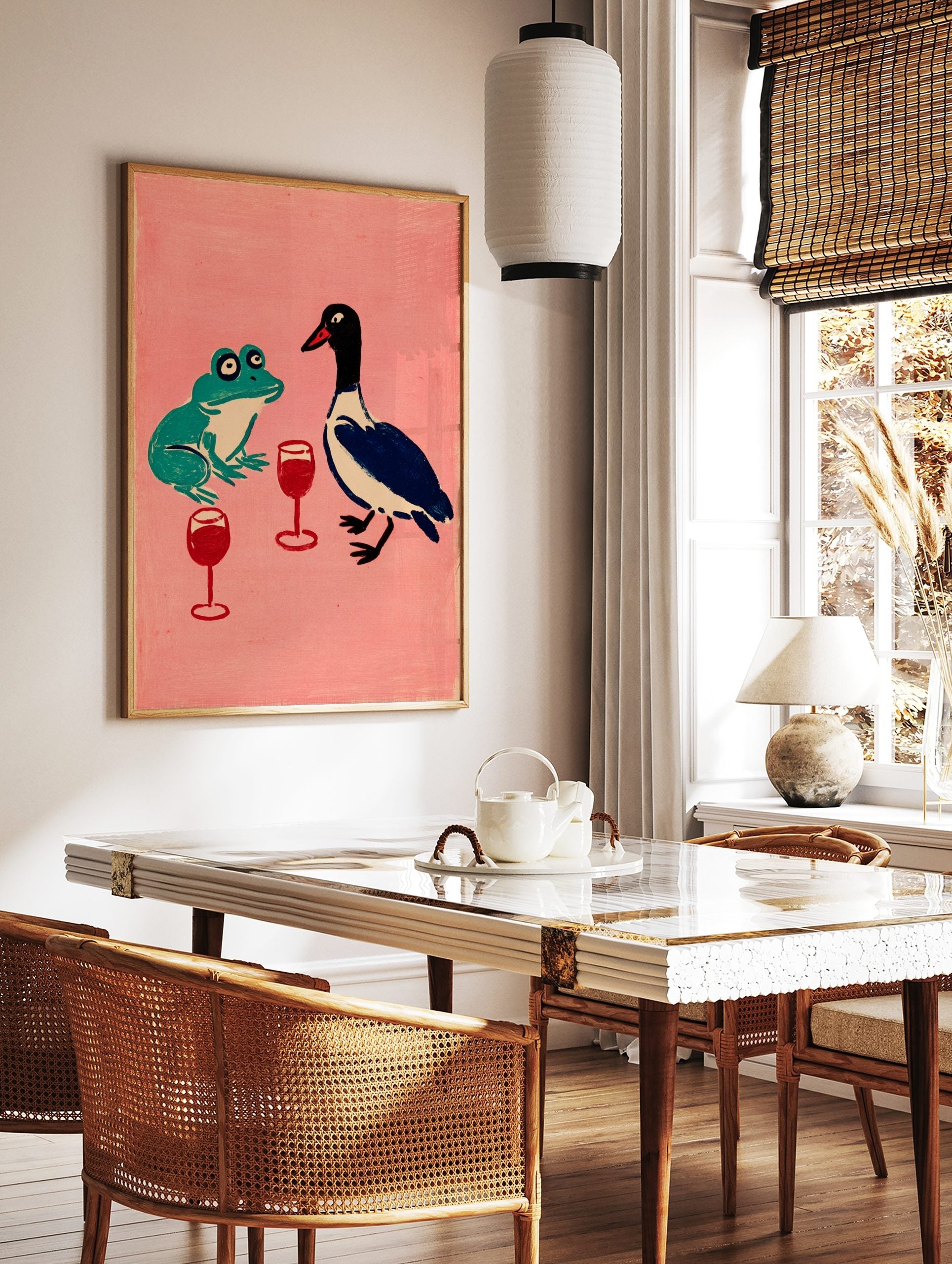 Illustrative print of a green frog and blue duck with red wine glasses on a pink background, in a styled room mockup