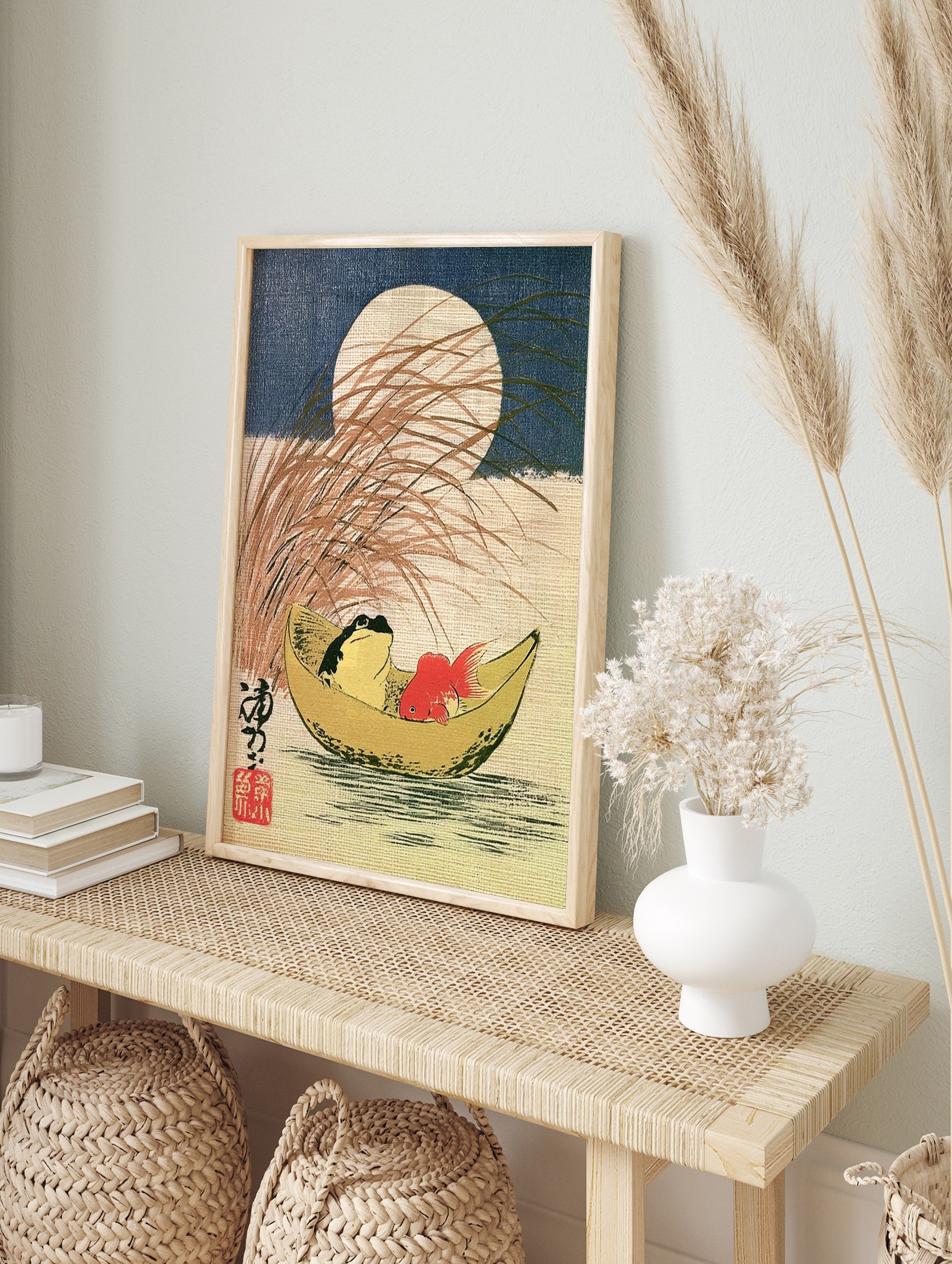 Japanese style art print of a frog and goldfish in a crescent moon boat with tall grass and a, in an alternate framed mockup