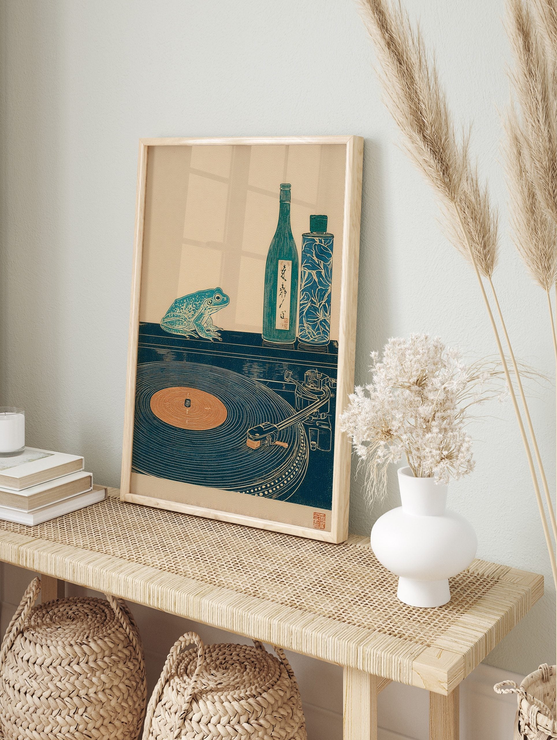 Japanese woodblock style print of a teal frog, sake bottle, and record player on a dark, in an alternate framed mockup