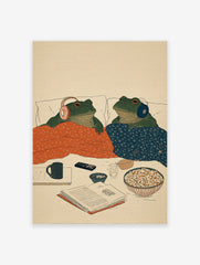 Illustration of two green frogs in bed with headphones, blankets, popcorn, and a book. Cozy frog art print.