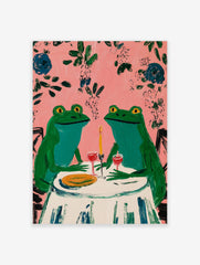 Two whimsical green frogs on a date at a table with wine and candle, pink background with leaves