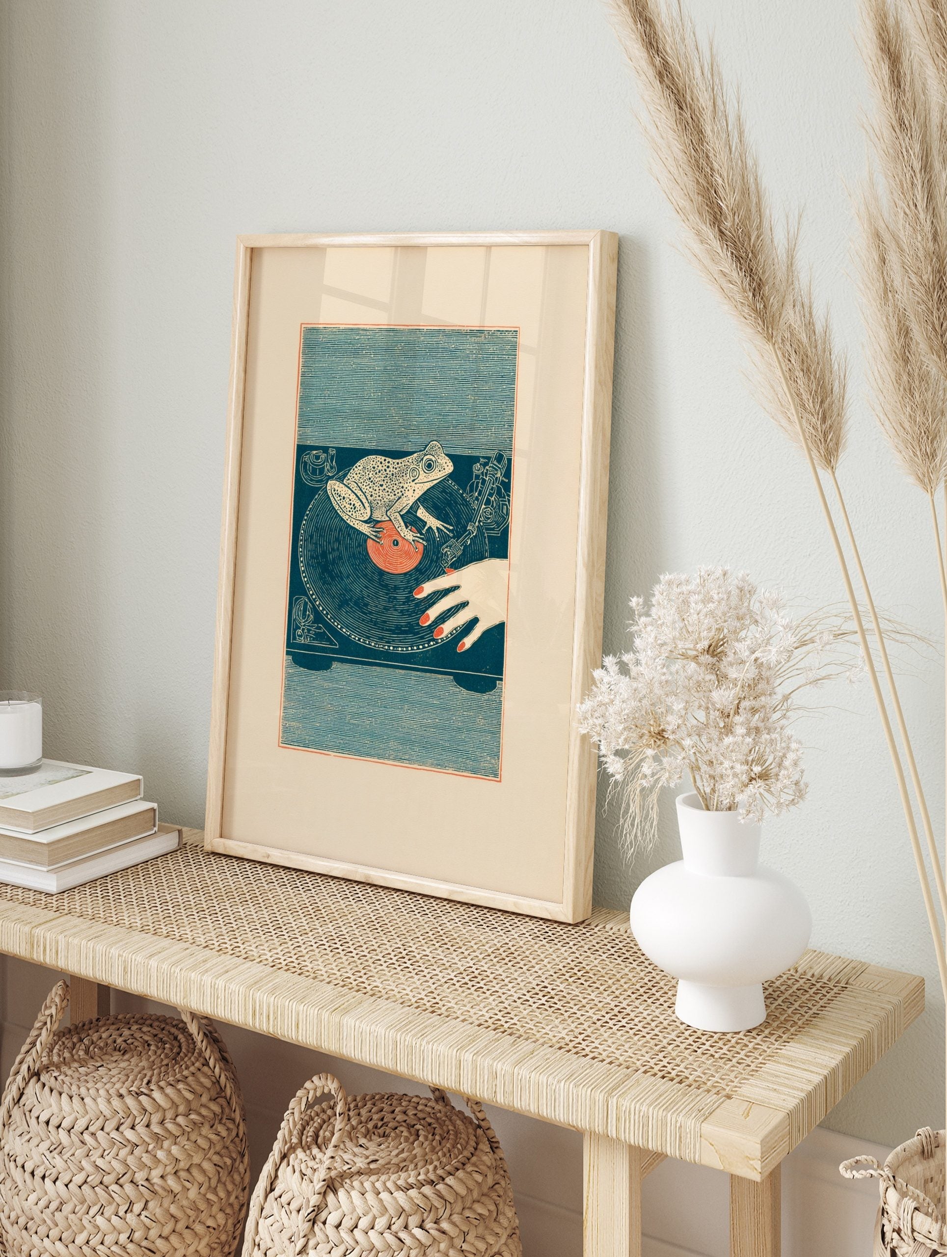 Illustrative frog DJ wall art on a turntable with a vinyl record and human hand, in an alternate framed mockup