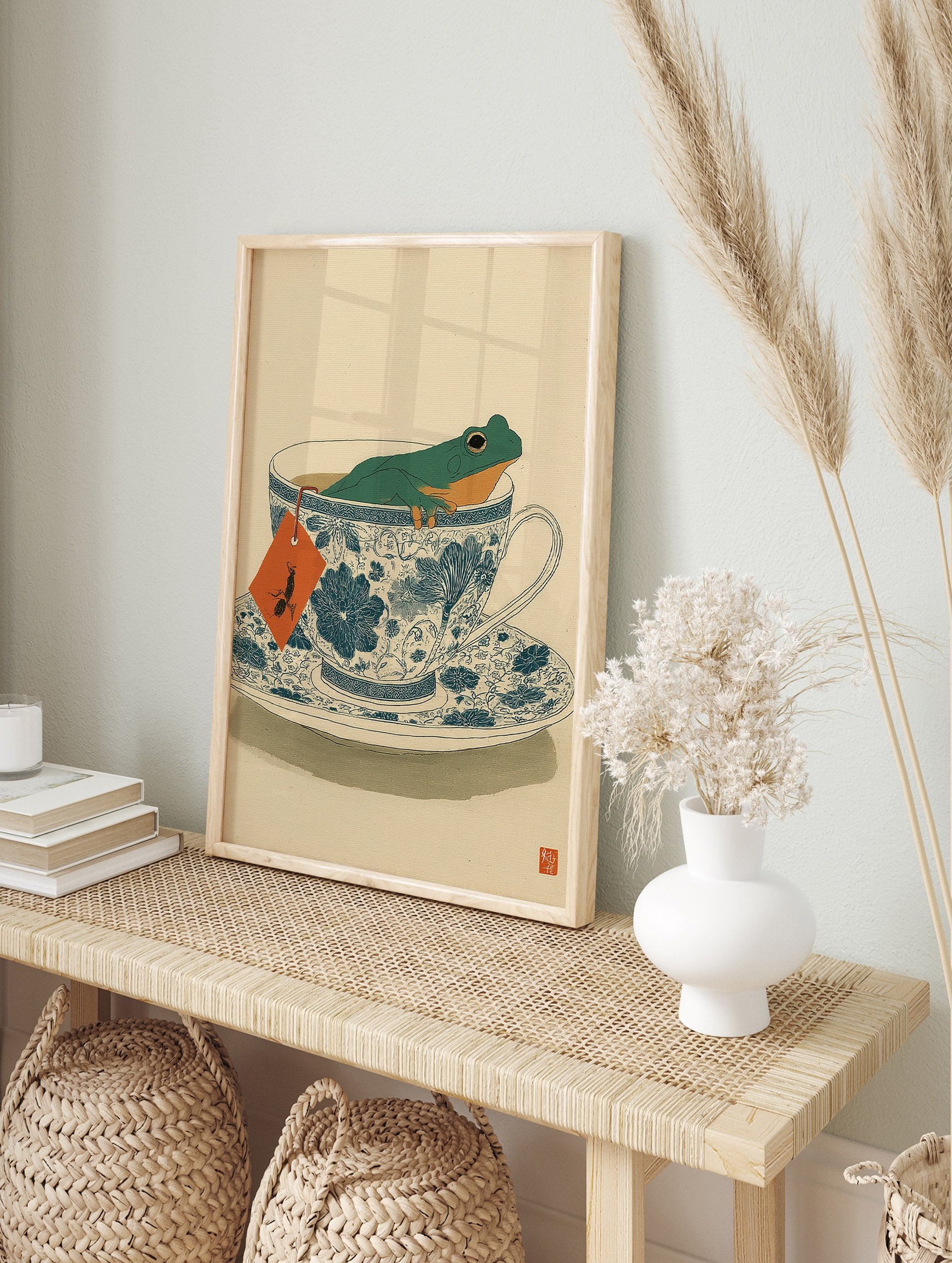 Green frog relaxing in a blue and white patterned teacup, with an orange tea bag tag, on a light beige background. - Image 3