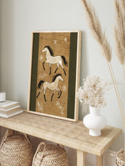 Two illustrative white horses with black manes and tails gallop on a textured tan background, in an alternate framed mockup