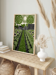 Green linocut print of a rural garden with sunflowers, cabbage, barns, trees, and a full moon, in an alternate framed mockup