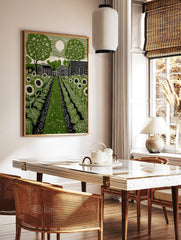Green linocut print of a rural garden with sunflowers, cabbage, barns, trees, and a full moon in a, in a styled room mockup
