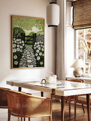 Linocut style print of a garden path leading to a wooden gate, flanked by white roses and green, in a styled room mockup