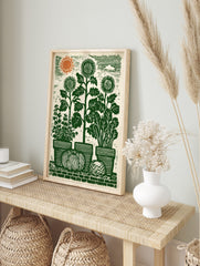 Green lino-cut style garden harvest print with sunflowers, potted herbs, pumpkin, and orange, in an alternate framed mockup