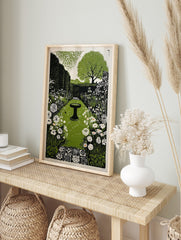 Linocut style garden path print with a bird bath, green hedges, white flowers, and a large, in an alternate framed mockup