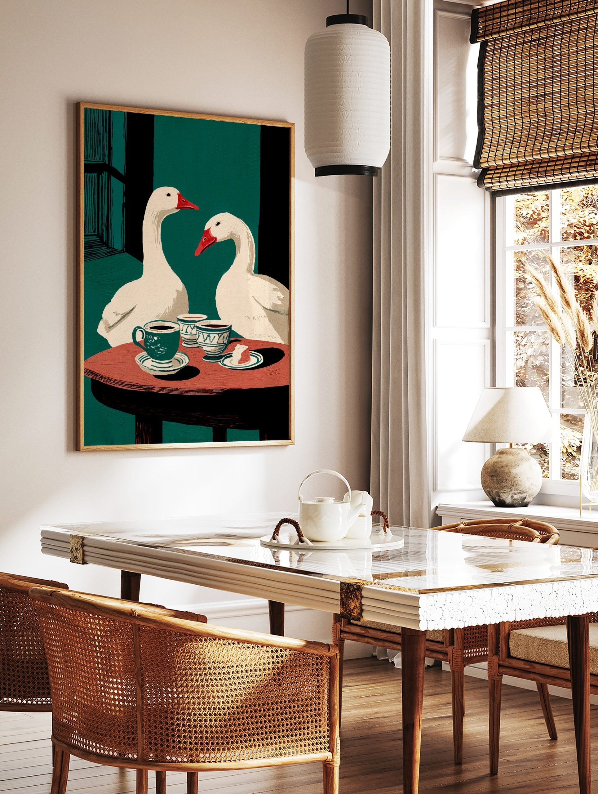 Illustrative wall art of two white geese with red beaks at a table with coffee cups and cake, in a styled room mockup