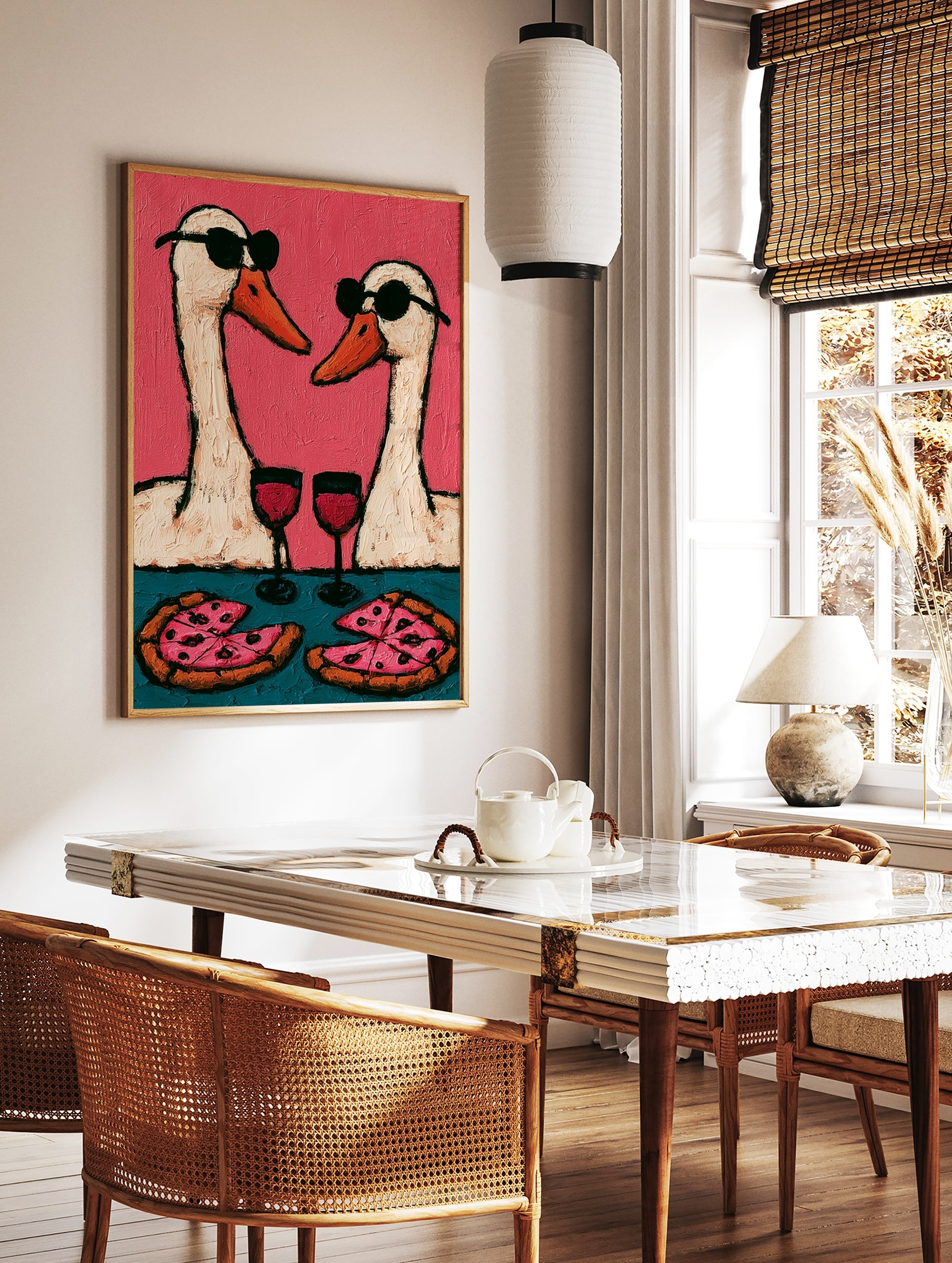 Playful wall art print of two geese wearing sunglasses, drinking wine, and eating pizza against a, in a styled room mockup