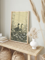 Illustrative print of two geese in a field of white cow parsley and daisies, earth tones, in an alternate framed mockup