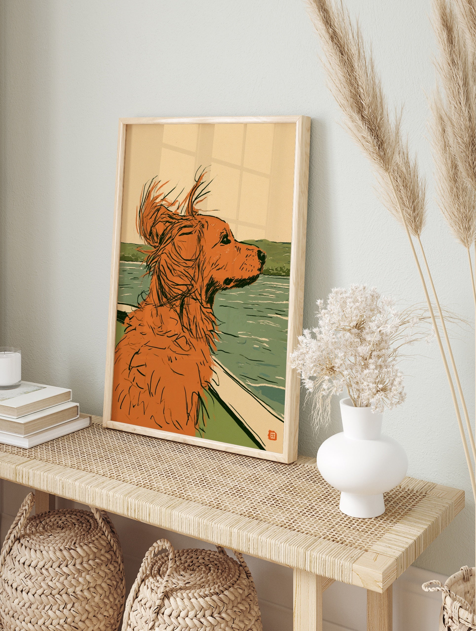 Illustration of a ginger dog looking out from a boat over calm water with green hills in the, in an alternate framed mockup