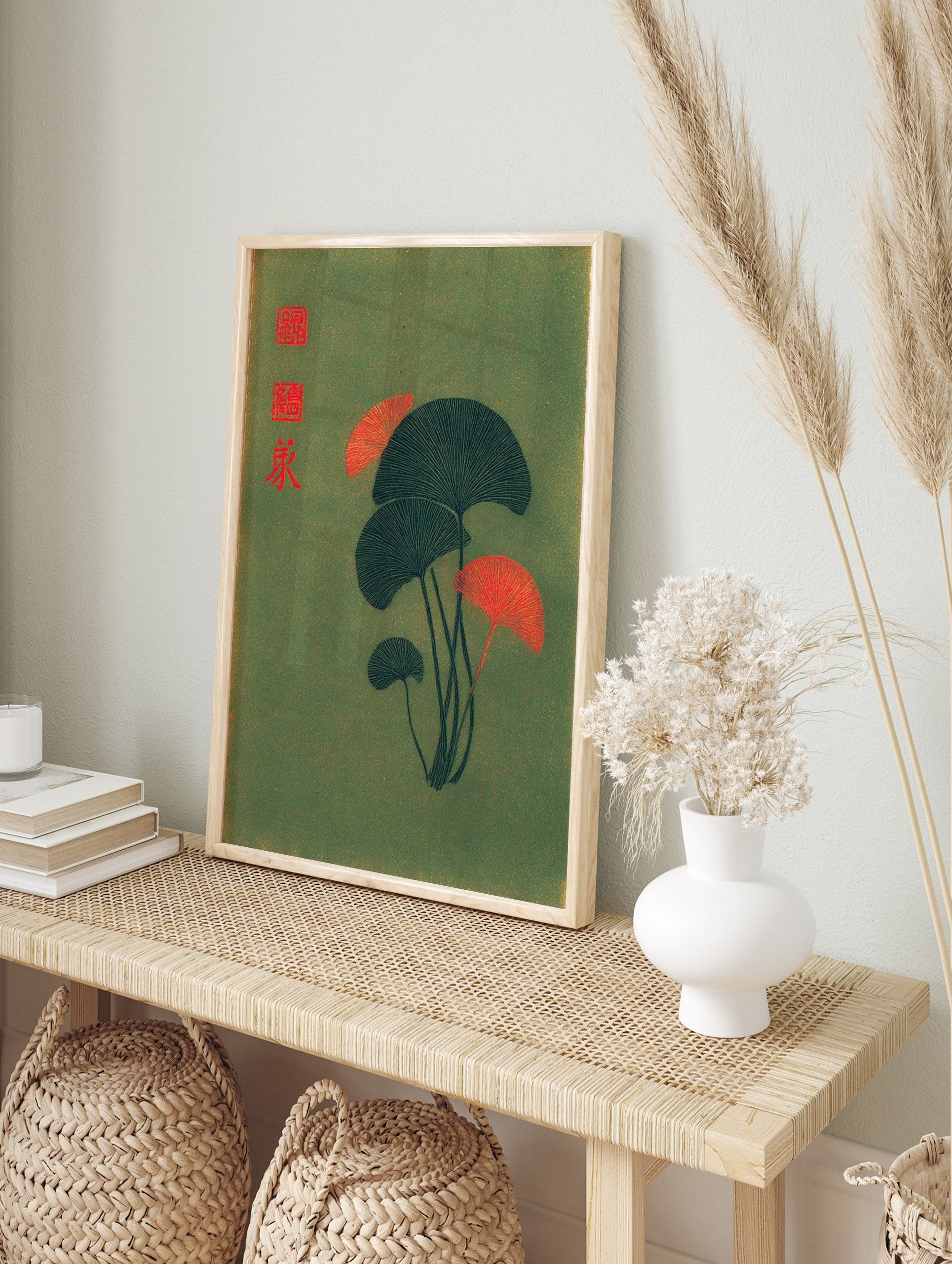 Stylised ginkgo leaves in dark teal and red-orange on a green background with red Japanese, in an alternate framed mockup