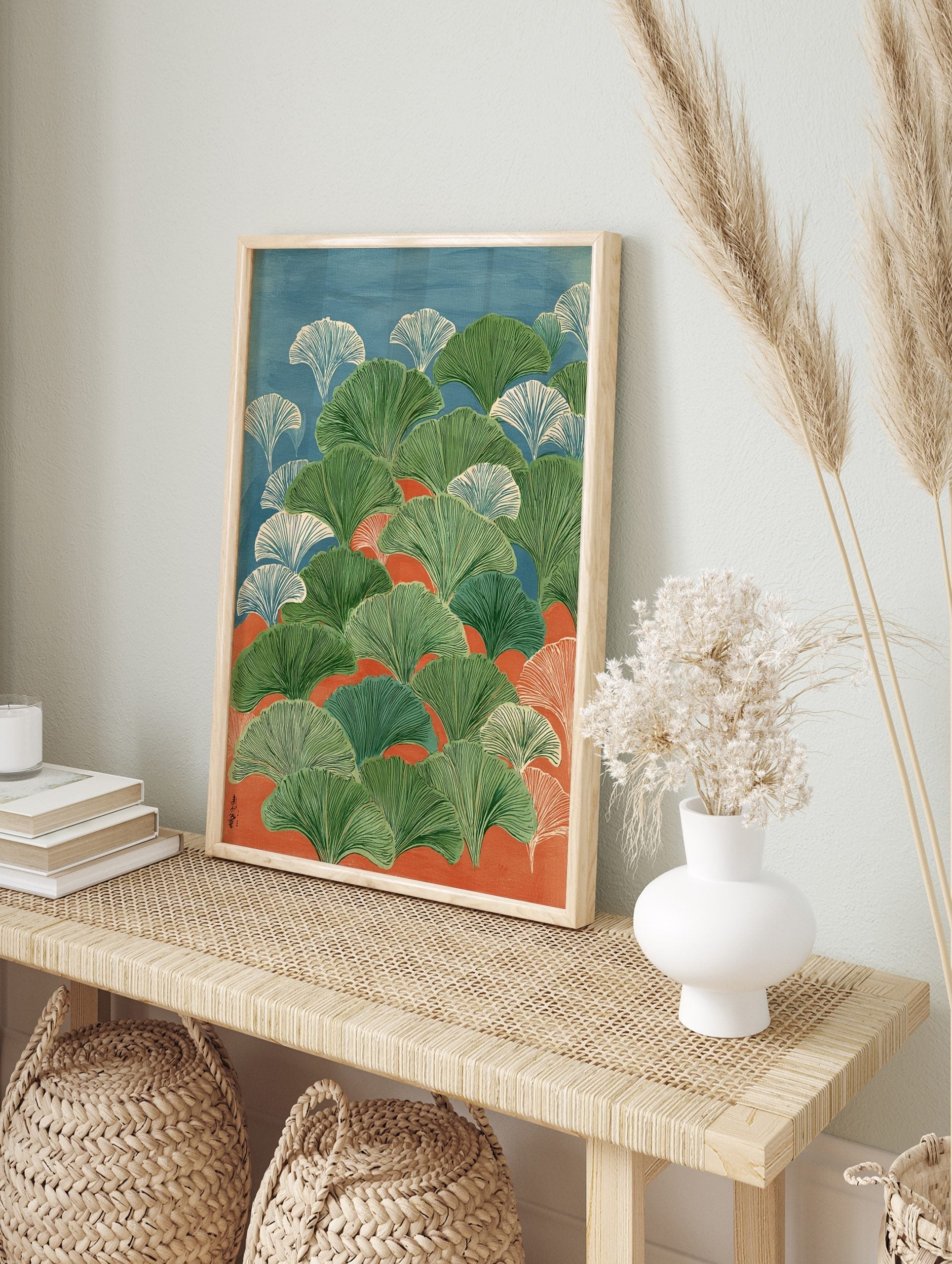 Illustrative ginkgo leaves in green and white against blue and orange background, in portrait, in an alternate framed mockup