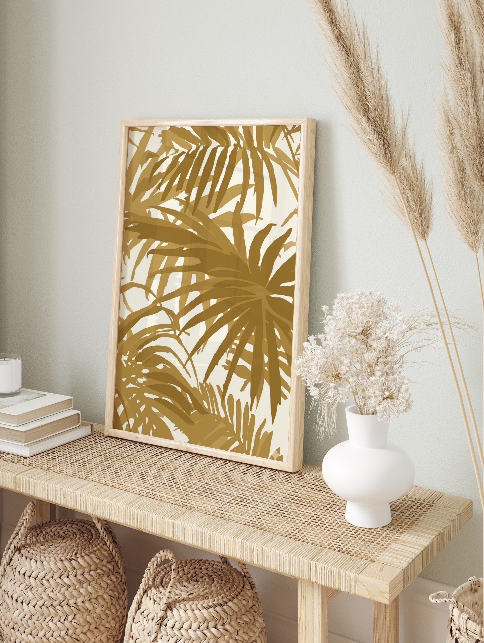 Gold palm leaf tropical botanical wall art print with overlapping foliage on a light background, displayed as the same artwork in an alternate framed wall art mockup