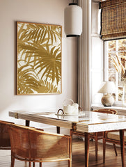 Gold palm leaf tropical botanical wall art print with overlapping foliage on a light background, displayed as the same artwork in a styled poster mockup for home decor