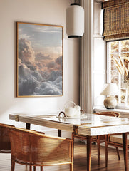 Photographic print of voluminous clouds bathed in warm golden and peach light at sunrise or sunset, in a styled room mockup