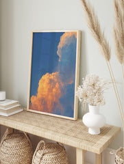 Dramatic golden orange sunset clouds against a clear blue sky, filling the frame with natural, in an alternate framed mockup