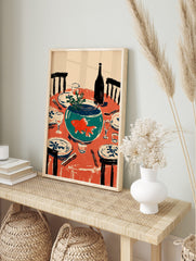 Illustrative wall art of an orange goldfish in a teal fishbowl on a red dining table set with, in an alternate framed mockup