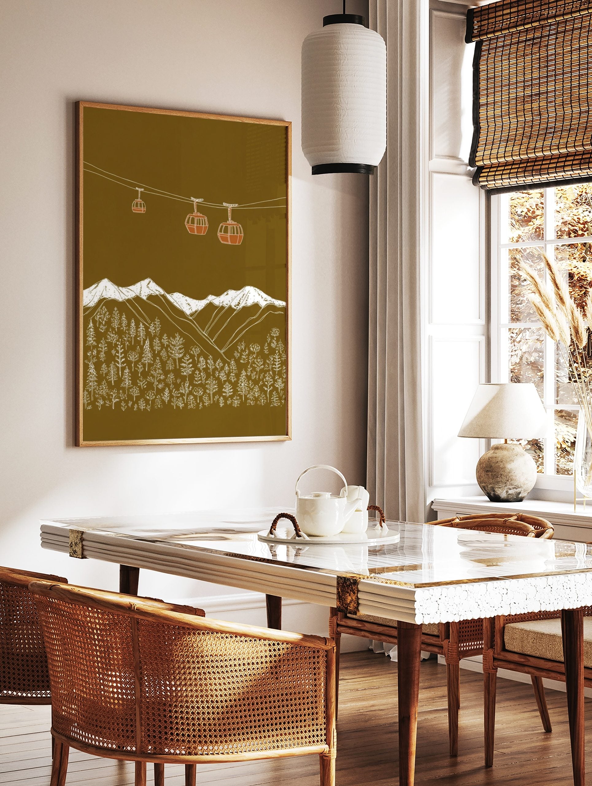 Illustrative gondola cabins above snow-capped mountains and forest on an olive green background, in a styled room mockup