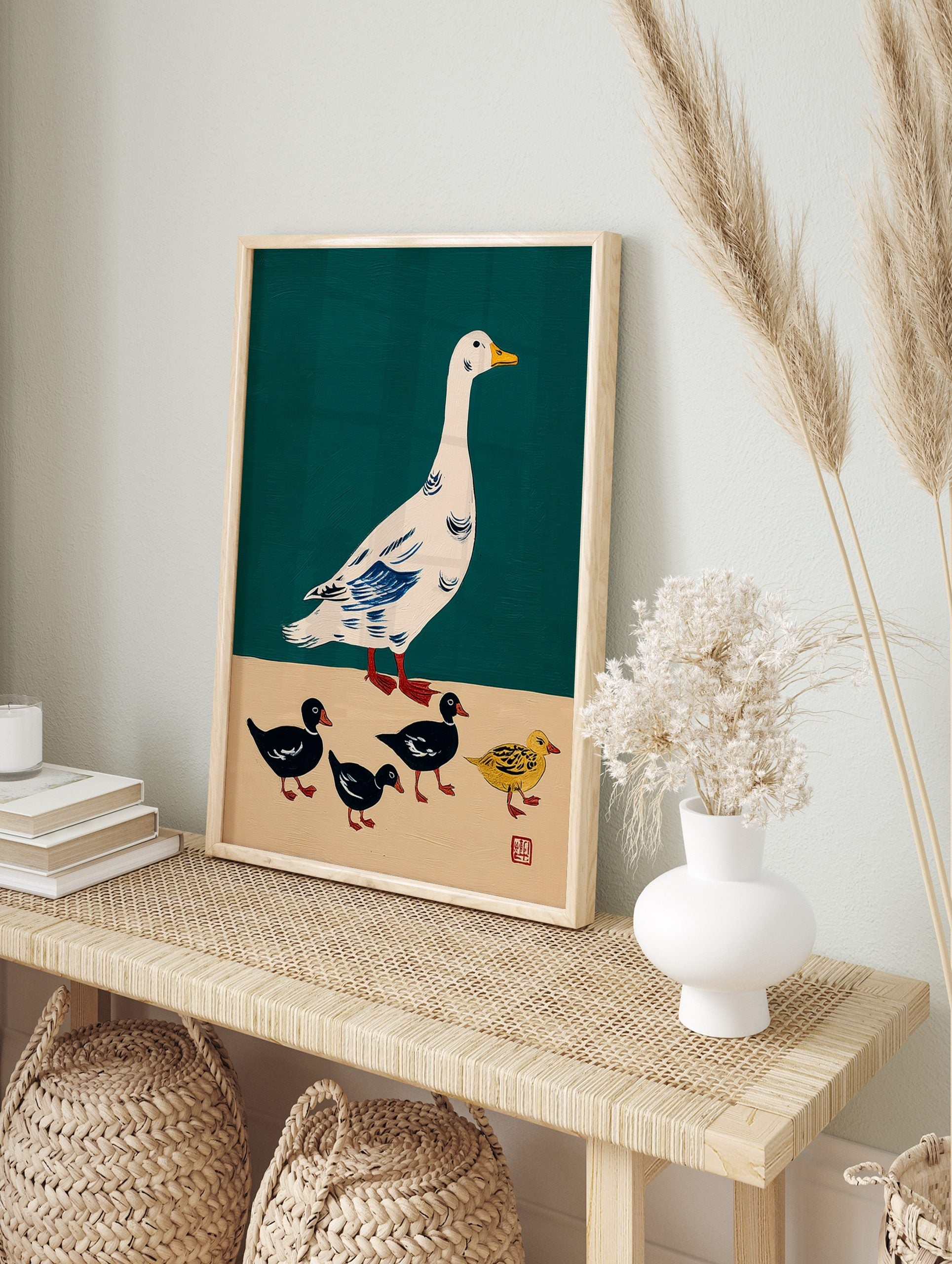 Illustrative print of a white goose with blue wings and four ducklings, three black and one, in an alternate framed mockup