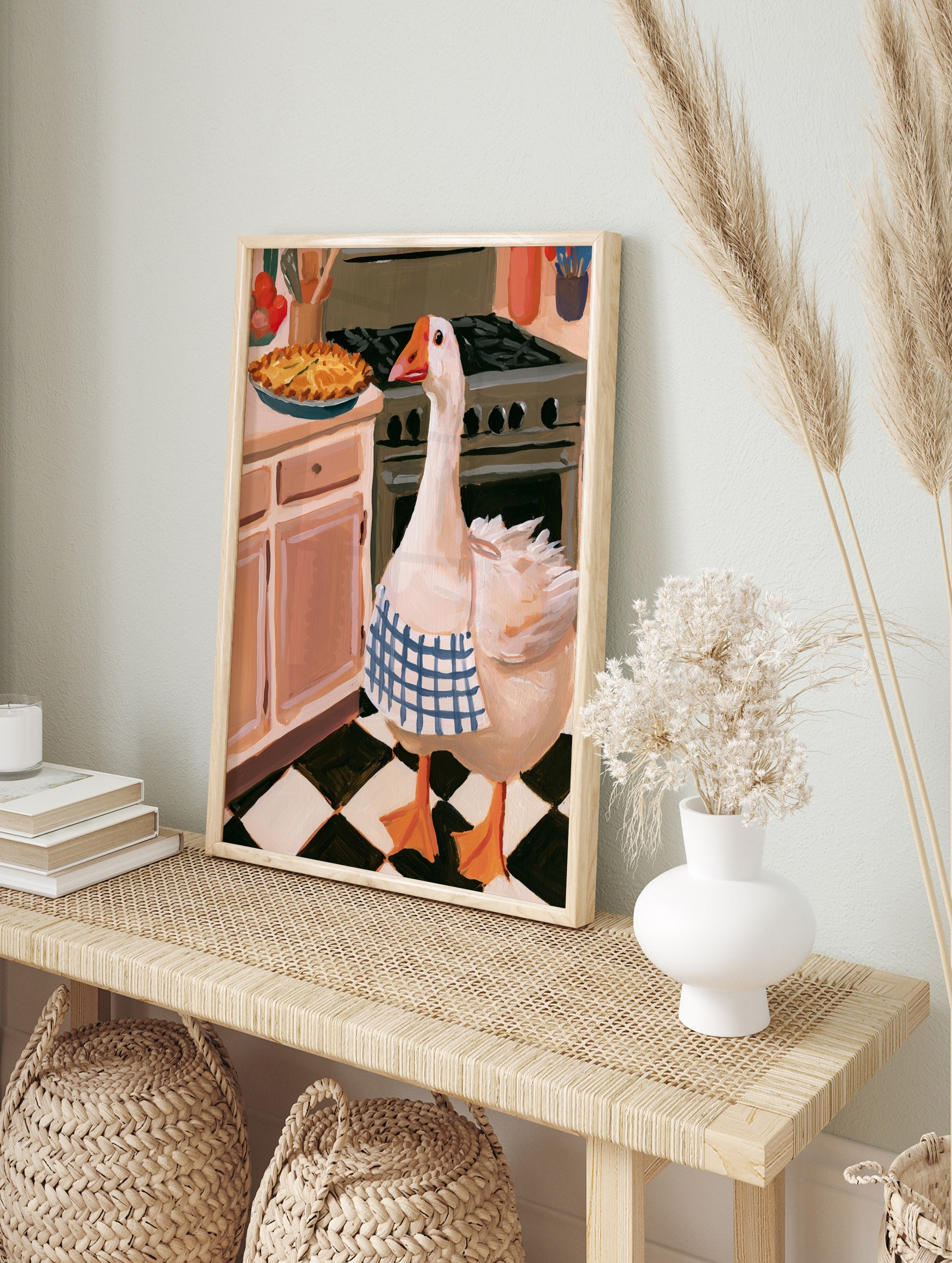 Illustration of a goose wearing a blue checkered apron standing in a kitchen next to a stove, in an alternate framed mockup
