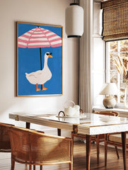 Playful illustration of a white goose in sunglasses under a pink and white striped beach umbrella, in a styled room mockup