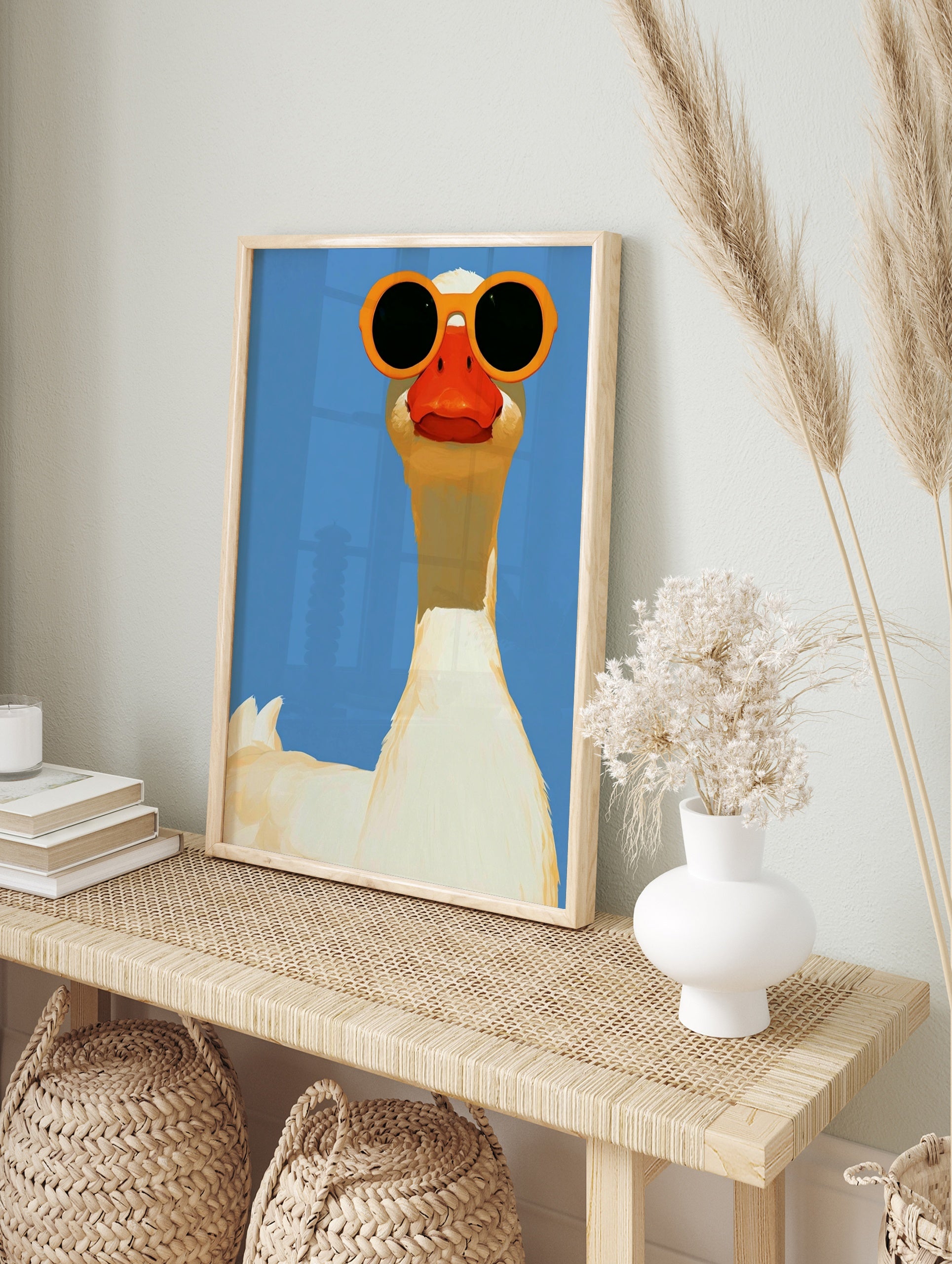 A white goose wearing large orange sunglasses against a solid blue background, illustrative, in an alternate framed mockup