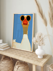 A white goose wearing large orange sunglasses against a solid blue background, illustrative, in an alternate framed mockup