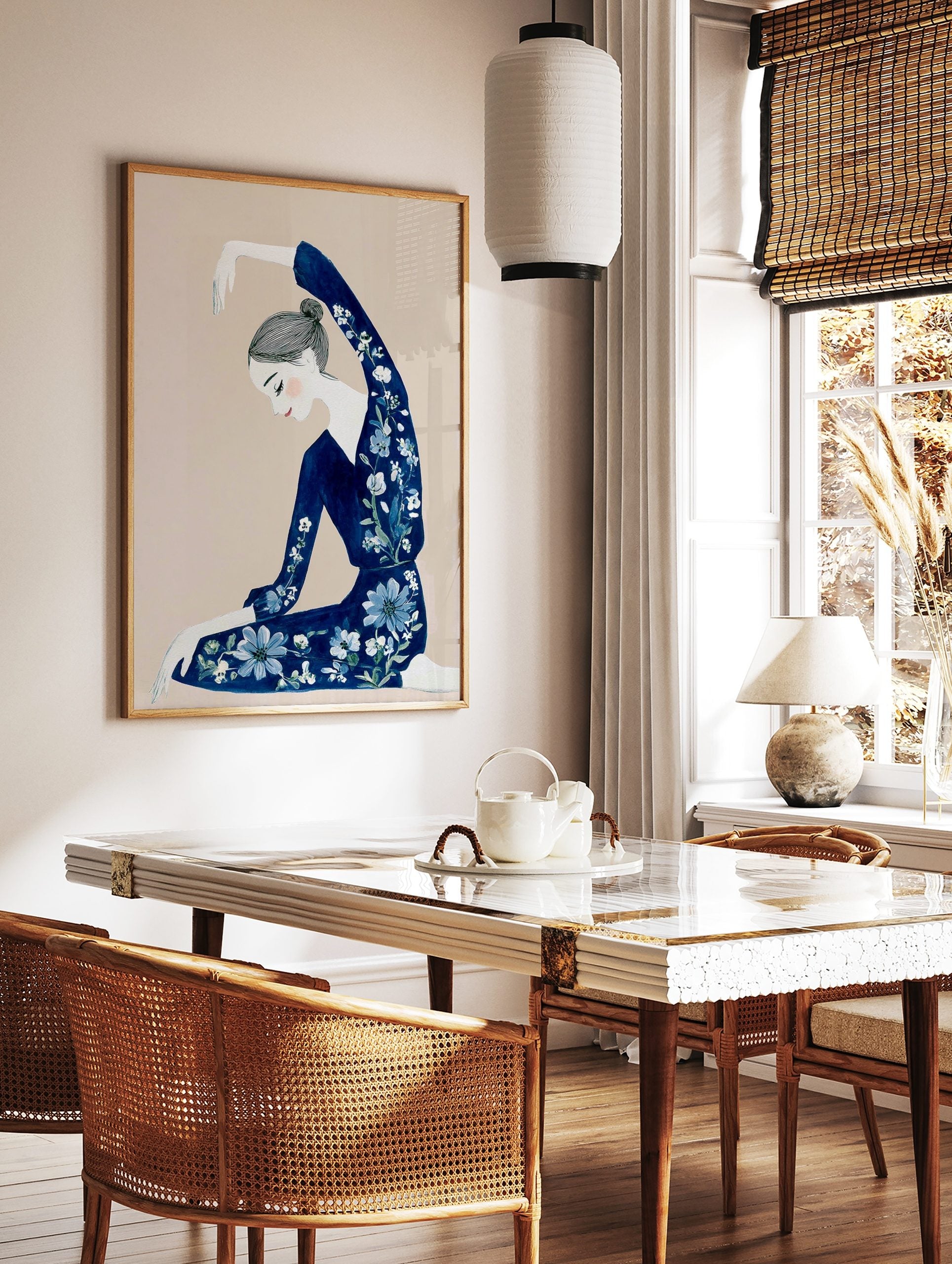 Illustrative art print of a woman in a navy floral outfit with arm raised, on a beige background, in a styled room mockup