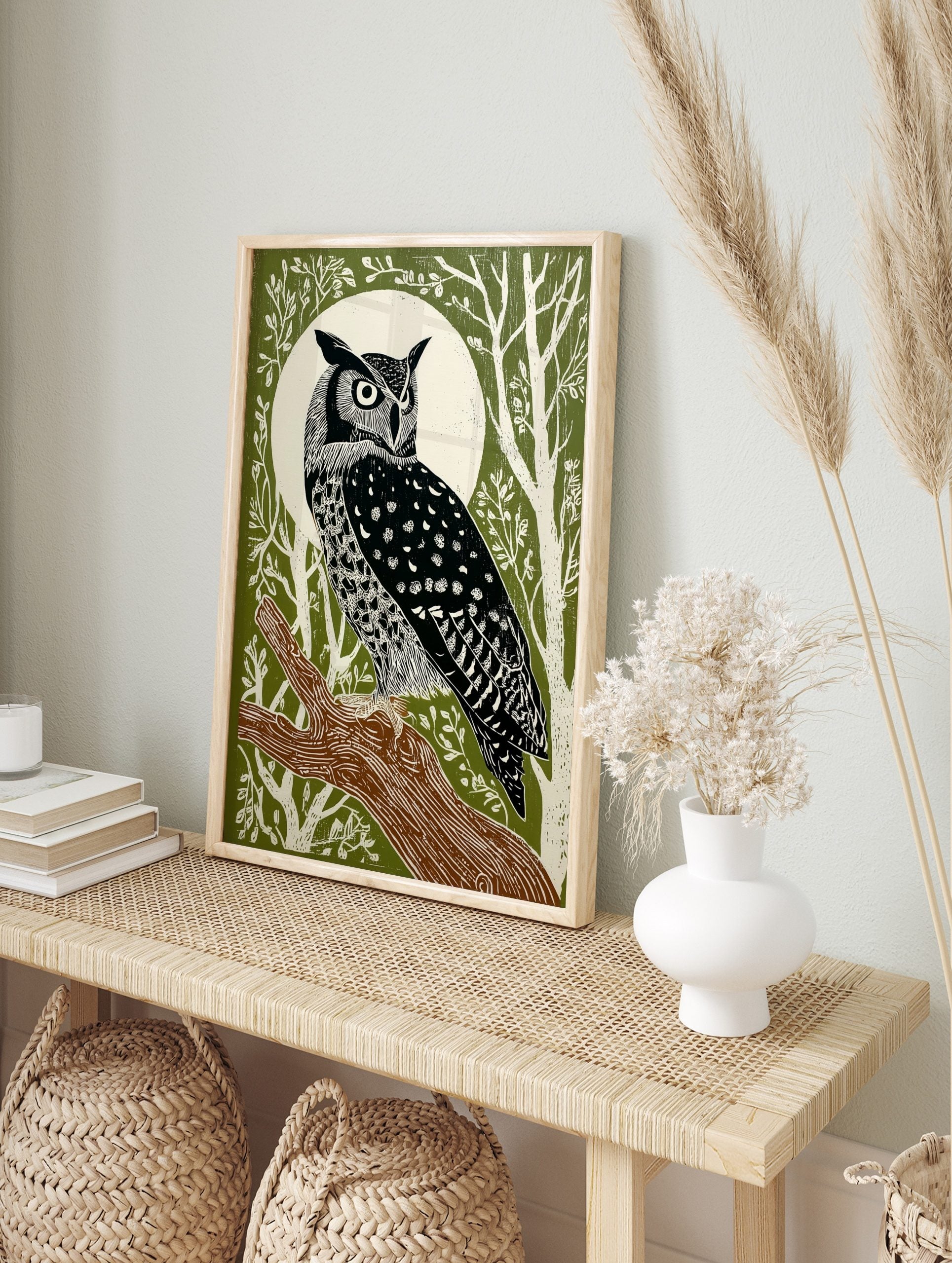 Illustrative great horned owl perched on a branch against a white full moon and green forest, in an alternate framed mockup
