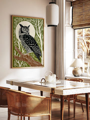 Illustrative great horned owl perched on a branch against a white full moon and green forest, in a styled room mockup