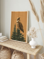 Illustrative great horned owl perched on a green evergreen tree branch against a warm tan, in an alternate framed mockup