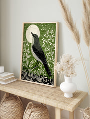 Illustrative green bird art print looking at a white moon, surrounded by white botanical, in an alternate framed mockup